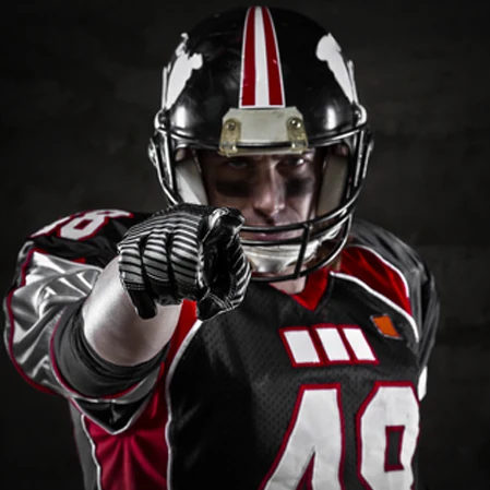 A dramatic photo of a football player in full uniform pointing at the viewer against a dark backdrop